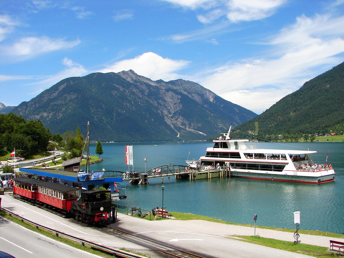 Achenseebahn + Achensee Schiffahrt: Lok 3 mit dem Zug nach Jenbach ist abfahrtbereit, kann man das Schiff  Stadt Innsbruck  kurz vor der Anfahrt nach Pertisau zu sehen im Hintergrund.