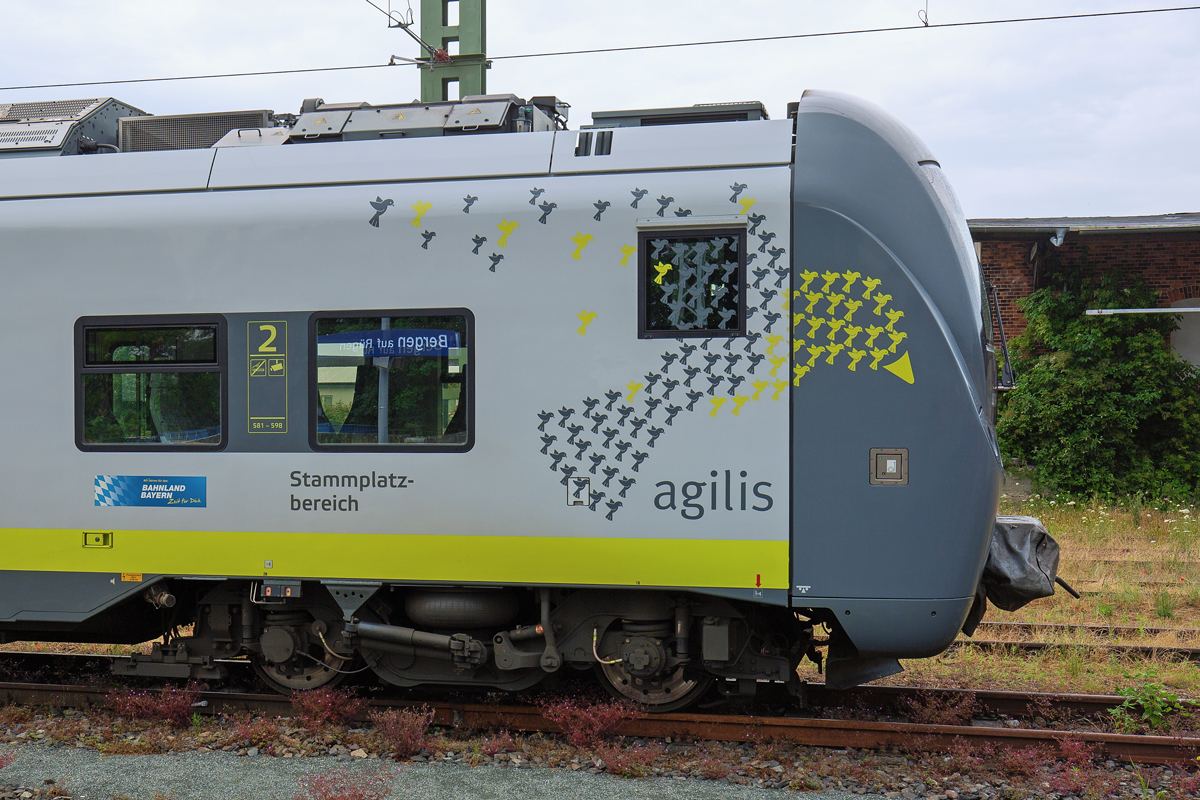 AGILIS Triebwagen und eine Schar kleiner Agilis Vögel als grosses Logo auf dem Fahrzeug. Die Reflexion im Seitenfenster verrät den Bahnhof Bergen. - 05.07.2021