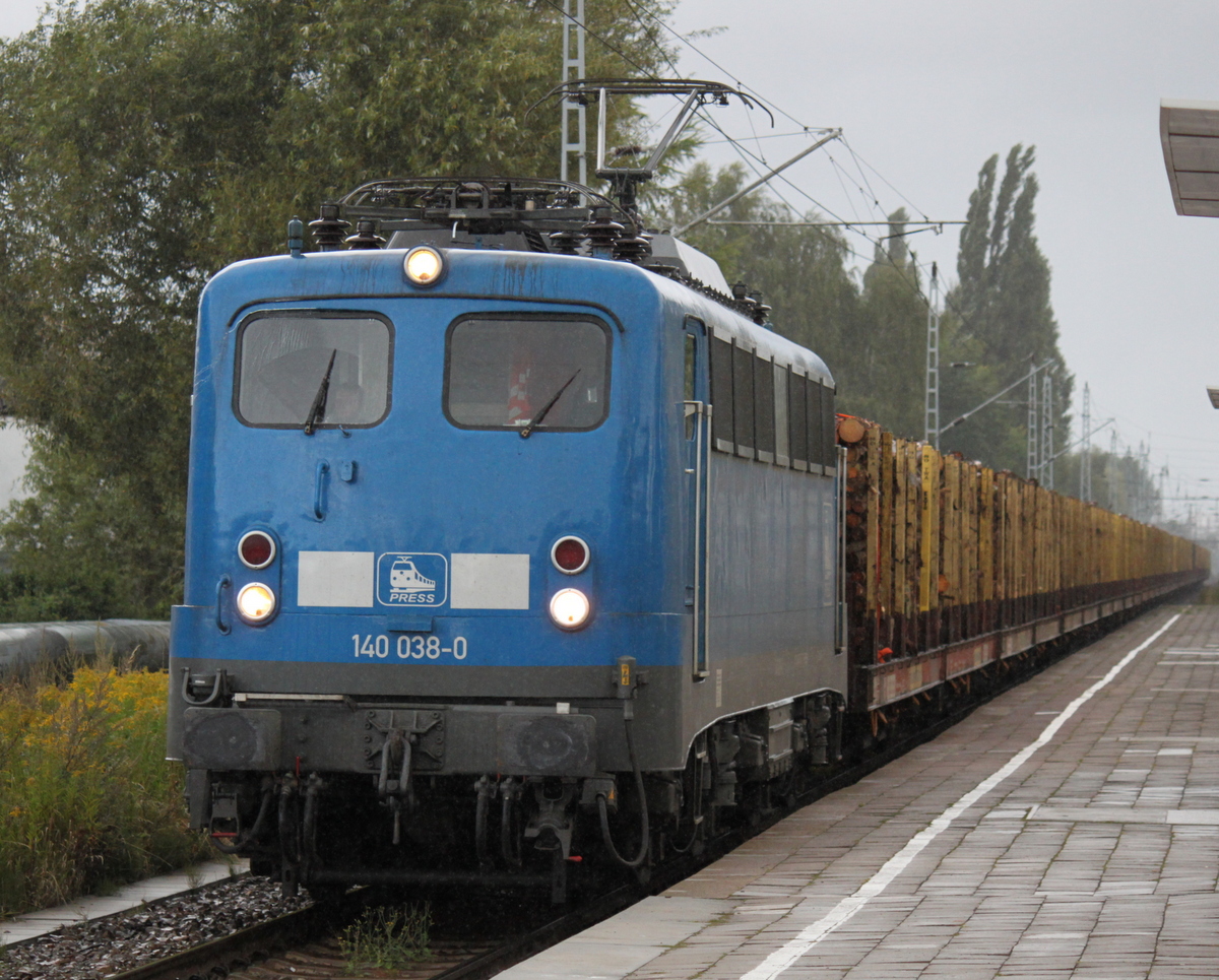 Alle meckern ber das Wetter auch bei Regen wird fotografiert 140 038-0 mit Holzzug von Rostock-Bramow nach Stendal-Niedergrne bei der Durchfahrt im Haltepunkt Rostock-Holbeinplatz.16.08.2014 