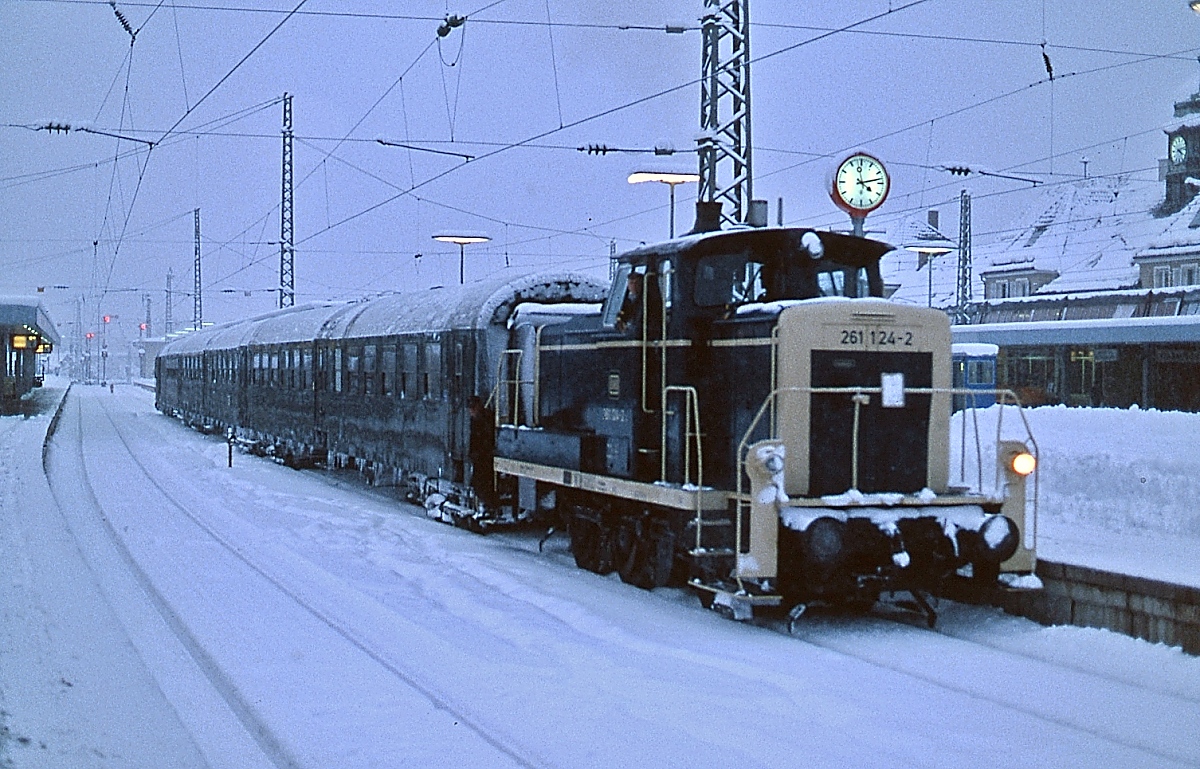  Alle reden vom Wetter - wir nicht  war ein bekannter Werbeslogan der Deutschen Bundesbahn. Trotz der heftigen Schneefällen um den Jahreswechsel 1979/80 lief der Schienenverkehr rund um Garmisch-Partenkirchen weiter. Hier bringt die 261 124-2 Anfang Januar 1980 eine kurz zuvor mit einer 1110 aus Innsbruck angekommene ÖBB-Wagengarnitur in die Abstellung. Wie ihre noch altrot lackierte Schwesterlok 261 123-4 war sie seit ihrer Abnahme am 09.07.1963 in Garmisch-Partenkirchen stationiert, die orange-beige Lackierung trug sie seit dem 19.06.1979.