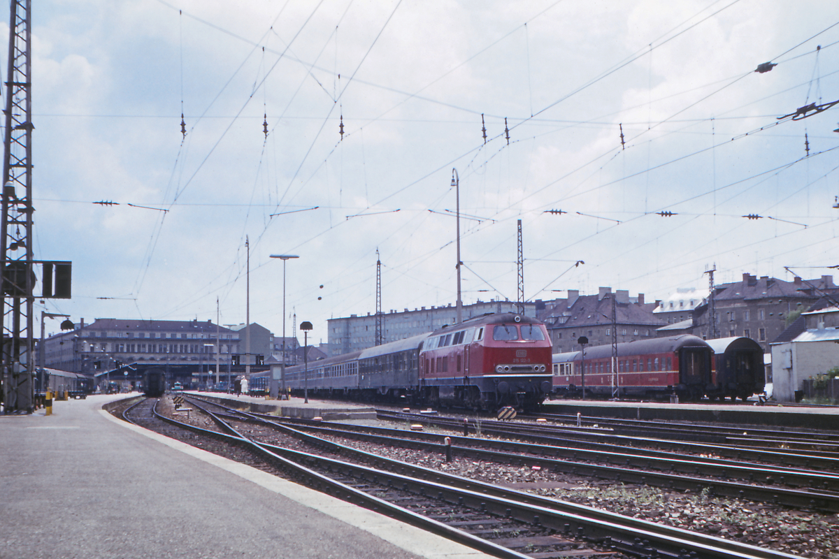 Aller Anfang ist schwer - Fotos der Jahre 1972 und 1973 gehören zu meinen ersten Eisenbahnfotos. Kamera war damals eine  Zeiss-Ikon_Voigtläner Vitessa AE  mithin eine Kleinbild-Sucher-Kamera mit automatischer Belichtung - sehr modern für die damalige Zeit.
Das Bild zeigt den Holzkirchner Flügelbahnhof des Münchener Hauptbahnhofs, von dort fuhren damals die Züge nach Mühldorf und nach Bayerischzell, Lengries und Tegernsee ab.
Abfahrtbereit auf Gleis 4 steht die 215 122-3, Bw Mühldorf, mit dem N2207 nach Mühldorf.
Die Gleise 1 - 4 verschwanden irgendwann in den 1990er Jahren, die 215er wurden bald durch fabrikneue 218er abgelöst. 
München Hbf, 2. Juli 1972