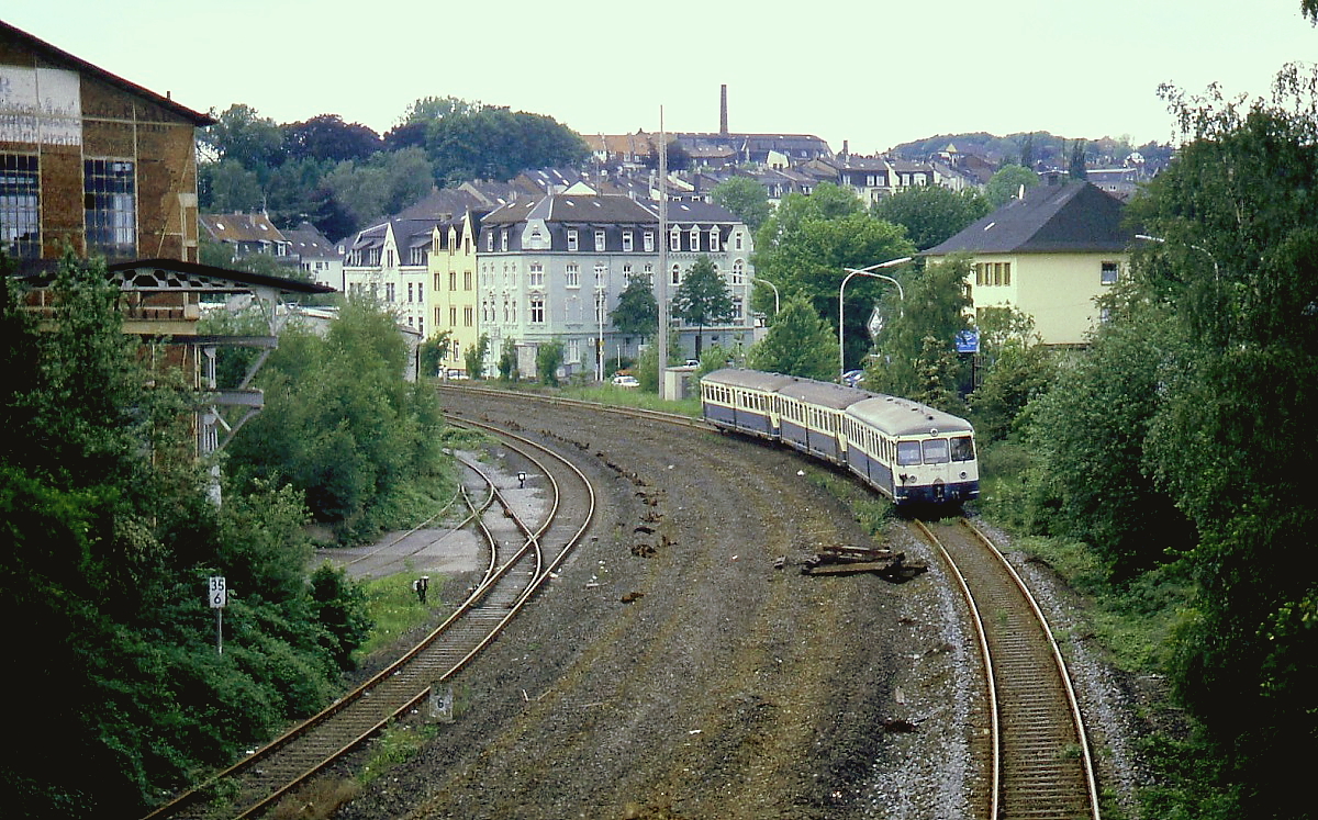 Als der 515 604-7 mit zwei 815 am 16.05.1993 die Wuppertaler Nordbahn im Rahmen einer Sonderfahrt befährt, ist von den einst umfangreichen Gleisanlagen in Wuppertal-Wichlinghausen nicht mehr viel übrig geblieben. Der Zug ist auf dem Reststück des früheren Streckengleises nach Hattingen unterwegs, auf der daneben liegenden Schotterfläche lagen früher die weiterführenden Gleise in Richtung Hagen.