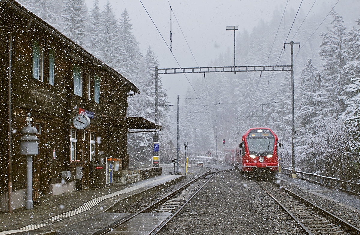 Als der ABe 4/16 3127 am 01.04.2022 eine Stunde nach der vorherigen Aufnahme in Davos Wiesen einfährt, schneit es immer noch heftig, allerdings war der Boden für eine Schneedecke nicht kalt genug. Auch in dieser Station gab es einen beheizten Warteraum (mit einer kleinen Ausstellung zum Bau des Wiesener Viadukts), ein Service, den man bei einem solchen Wetter zu schätzen weiß!