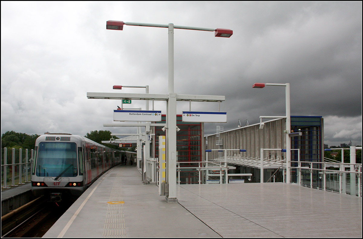 Als es noch Regenwolken gab -

... fuhr unser Zug in Richtung Rotterdam Innenstadt auf der oberen Bahnsteigebene in die Station Tussenwater ein. Die Bahnsteigbeleuchtungskörper sind farblich an die jeweilige Linie angepasst, rot für die Calandlijn, blau für die Erasmuslijn.
Später an jenem Tag mussten wir uns vor einem sehr heftigen Wolkenbruch in Sicherheit bringen.

21.06.2016 (M)