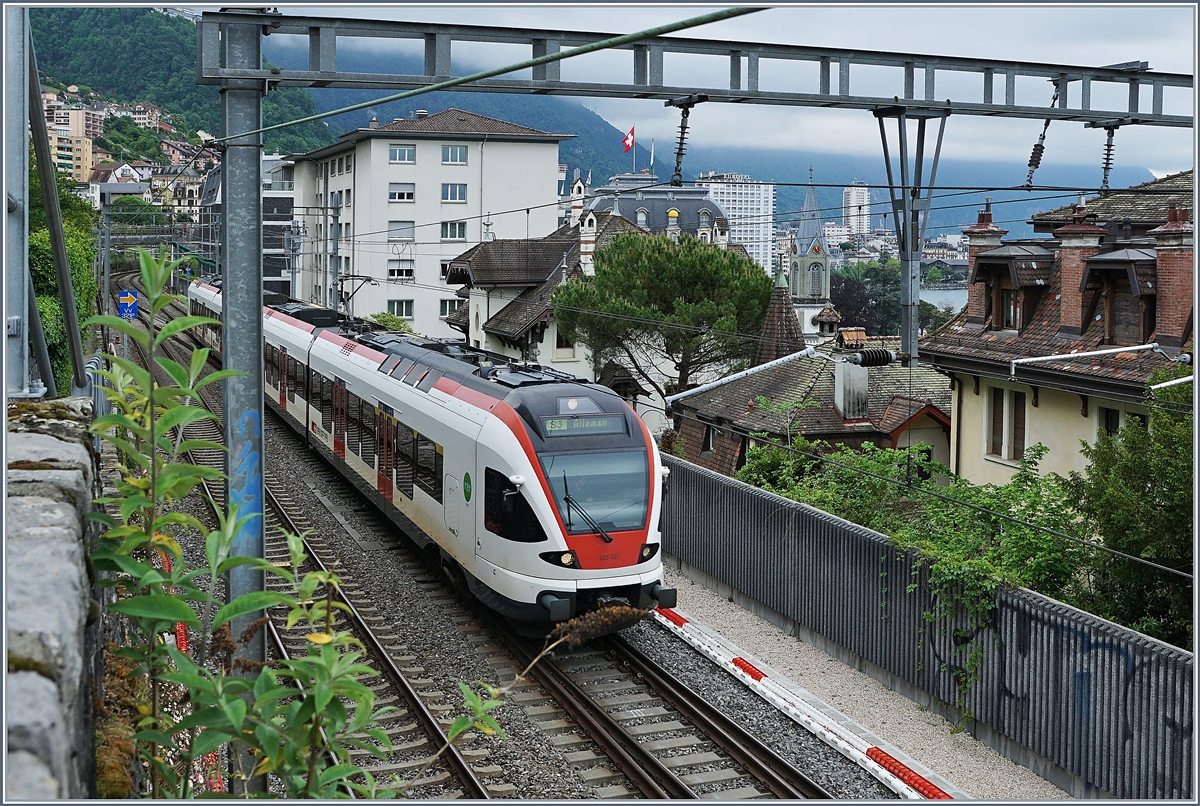 Als hier 2. April 1861 die Strecke von Lausanne nach Villeneuve eröffnet wurde, führte das Trasse noch durch die Rebberge ausserhalb von Montreux. Heute sind Montreux und Clarens praktisch zusammengewachsen und die Trasse führt zwischen mehr oder weniger hübschen Häusern entlang, doch in der Regel beschäftigen sich die Reisenden kaum mit dem bewundern der Landschaft. Doch wer bei diesem Bild genauer hinsieht, entdeckt, dass die Landschaft, welche die Reisenden nach Montreux lockt gar nicht so weit entfernt ist. 
Somit ist der gezeigte Zug eigentlich Mittel zum Zweck, den Streckenabschnitt etwas in die Landschaft einzuordnen: In der Bildmitte mit dem Schweizer Fahnen auf dem Dach ist prächtige Montreux Palace zu erkennen, auf diesem Bild gleich daneben, das Eurotel, dann folgt der Kirchturm der evangelischen, deutschsprachigen Kirche von Montreux, dessen Ähnlichkeit mit der Gedächtniskirche von Berlin kein Zufall ist, in der Ferne reckt sich der Tour D'Yoire in die Höhe und mit etwas guten Willen entdeckt man auch den See, den Lac Léman. 

6. Mai 2020