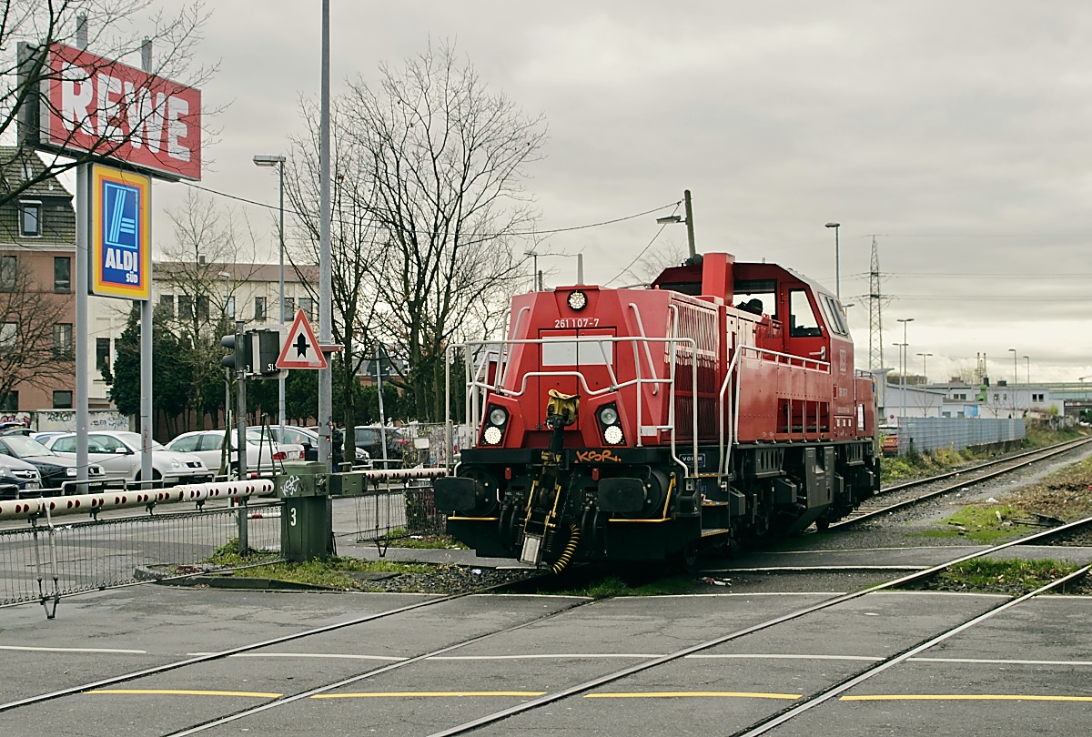 Als Lz kehrt die 261 107-7 am 24.01.2018 aus Düsseldorf-Lierenfeld zurück. Hier überquert sie den beschrankten Bahnübergang an der Bruchstraße. Gleich wird sie ihre Fahrt über das rechte Gleis in Richtung Abzweig Dora fortsetzen.