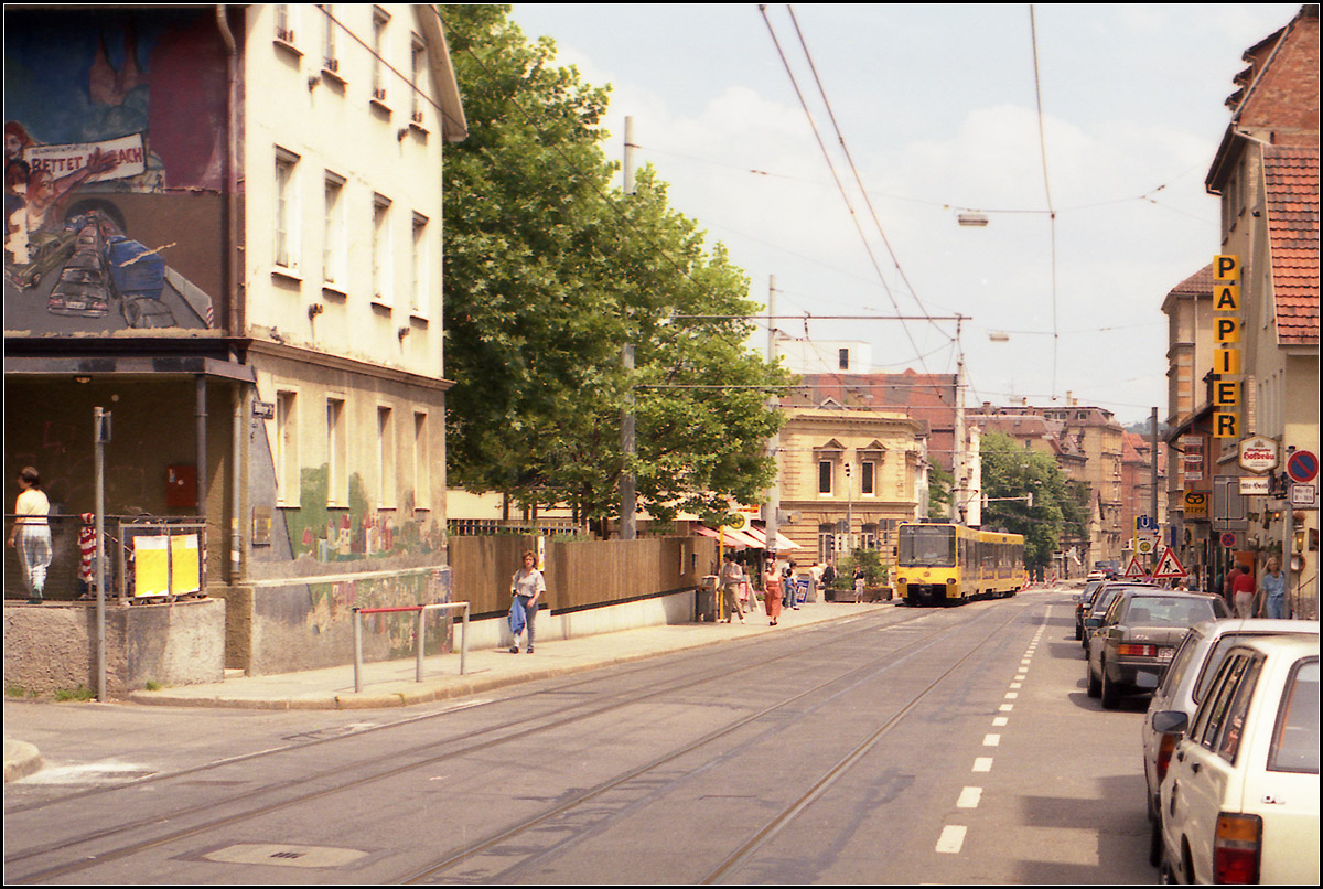 Als die Stuttgarter Stadtbahn noch jung war -

Ein Zug der Linie 14 erreicht die Haltestelle 'Schreiberstraße' in Heslach. Während stadtauswärts vom Gehsteig aus eingestiegen werden konnte, musste in Richtung Innenstadt von der Straßenfahrbahn in die Stadtbahn eingestiegen werden, was es nirgendwo sonst in der Geschichte der Stadtbahn Stuttgart gab.
Mit dem Hochbahnsteigbau in Mittellage wurde die Haltestelle 1998 etwas in Richtung Innenstadt an den 'Erwin-Schoettle-Platz' verlegt, was auch zu einem Namenwechsel führte. 

Scan vom Farbdia, Ende der 1980iger Jahre