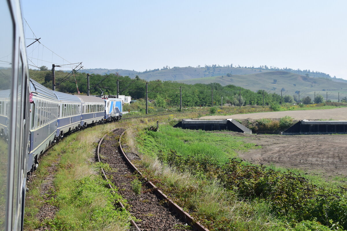 Alt und Neu. Eines der größten Bahnprojekte in Rumänien ist aktuell die Modernisierung und Neutrassierung der Bahnstrecke Sighisoara nach Brasov. Überall auf den 130km langen Abschnitt wird kräftig gebaut. Bei Mateias sieht man gut den neuen Trassenverlauf. Die Trasse wird hier durch einen Tunnel kommen und den Berg durchqueren statt wie aktuell umfahren. Das zweite Streckengleis der Bestandsstrecke ist bereits stillgelegt und teilweise abgebaut worden.

Mateias 02.09.2025