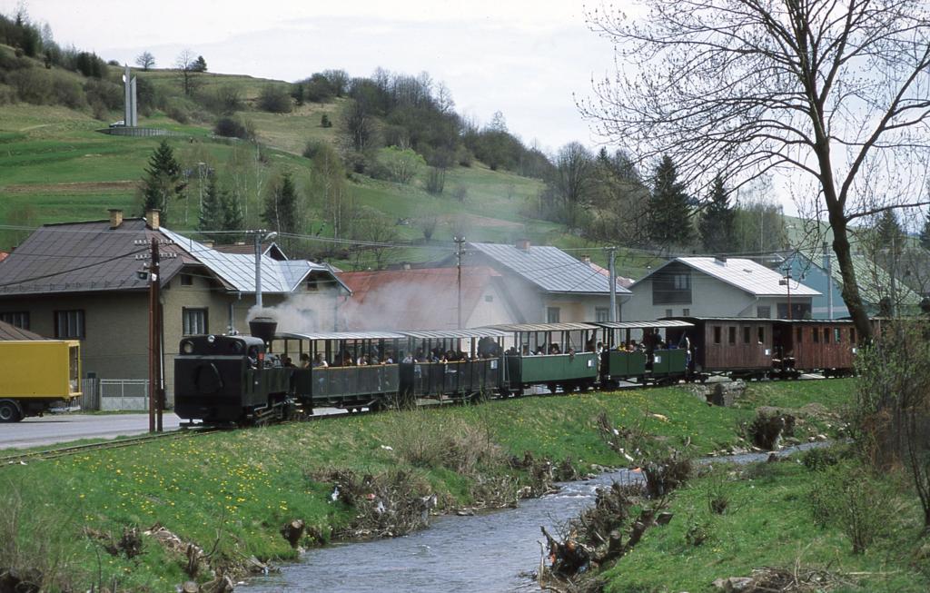 Am 1. Mai 2003 war, wie eigentlich in jedem Jahr an diesem Tag, wieder
viel Betrieb auf der Schmalspurbahn Cierny Balog. Ein langer Zug mit
Lok 5 an der Spitze hat gerade den Bahnhof verlassen und fhrt nun am
Bach entlang durch das Dorf. 