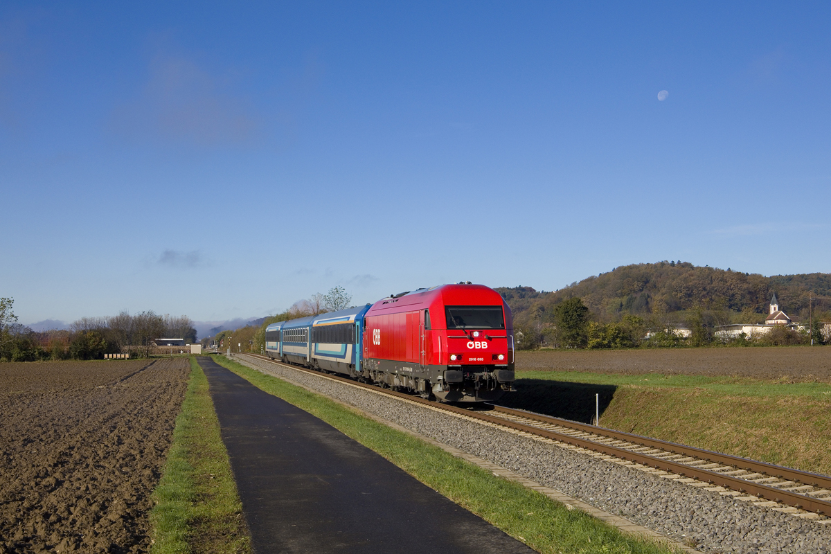 Am 1. November 2023 war 2016 095 mit dem IC 311  Drava  (Ljubljana - Tatabánya) unterwegs. Hier hat der Zug soeben die Haltestelle Lödersdorf ohne Halt durchfahren und wird wenige Minuten darauf den Bahnhof Fehring erreichen. 