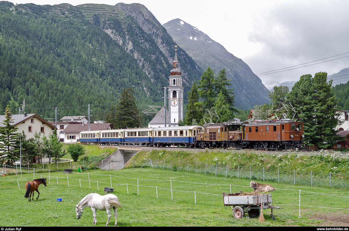 Am 10. Juli 2014 befinden sich die nur noch selten eingesetzte Ge 4/6 353 und Ge 6/6 415  Krokodil  auf Sonderfahrt mit den Pullman Wagen der RhB. Hier bei der Ortsausfahrt von Bever in Richtung Unterengadin.
