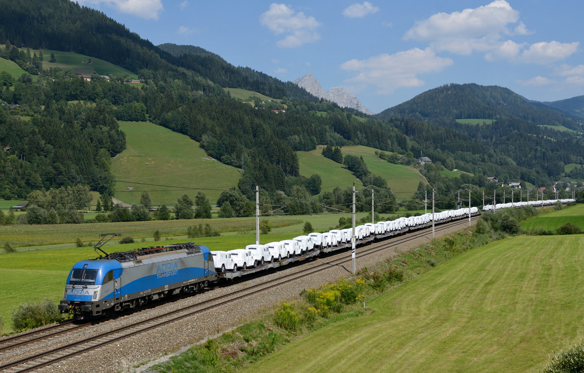 Am 10.08.2015 bespannte die 1216 922  Adria Transport  den LTE-Autozug 48996 welcher nagelneue G-Klassen von Messendorf nach Bremerhaven brachte, fotografiert bei Rottenmann. 