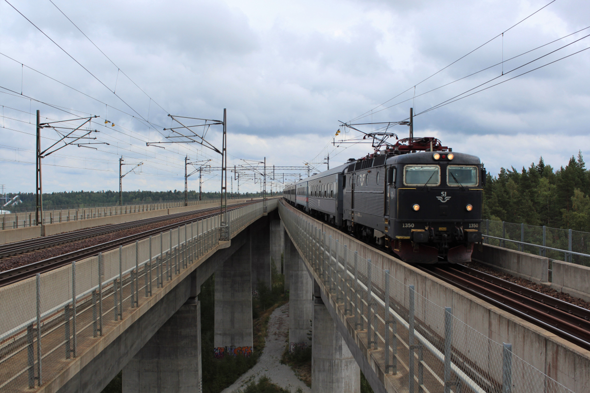Am 10.09.2018 erreicht eine RCc5 mit ihrem RE933 nach Eskilstuna den Bahnhof Södertälje Syd. Dieser wurde im Zuge der Neubaustrecke von Järna nach Flemingsberg im Jahr 1995 neu errichtet. Auf einer über zwei Kilometer langen und fast 50m Hohen Brücke überqueren die Züge eine Verbindung des Mälarsees in die Ostsee und Teile des Industriehafens von Södertälje. Der Bahnhof Södertälje Syd befindet auf dem südlichen Ende der Brücke. Standort des Fotografen war das frei zugängliche Bahnsteigende. 