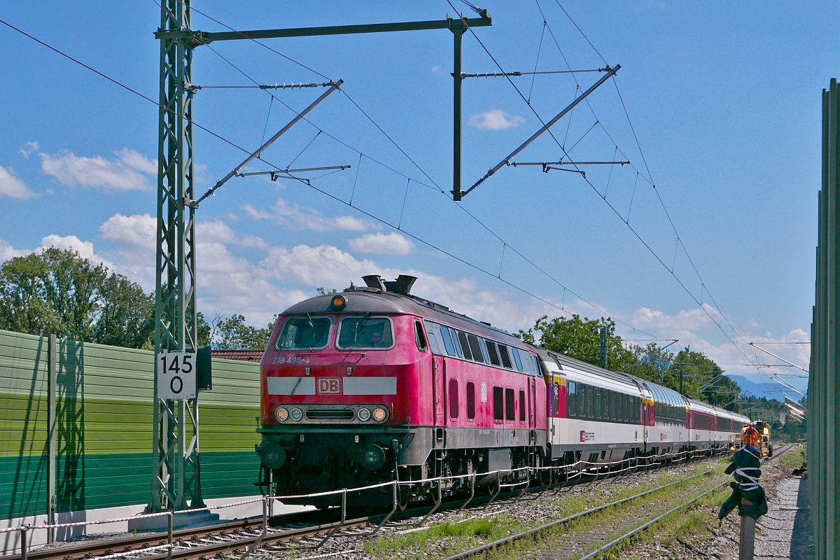 Am 12.07.2020 ist am Bahnbergang in Oberreitnau die Lrmschutzwand nur auf einer Seite fertig. 218 498-4 befindet sich mit den von Zrich kommenden Wagen des EC 195 auf der Fahrt nach Mnchen.