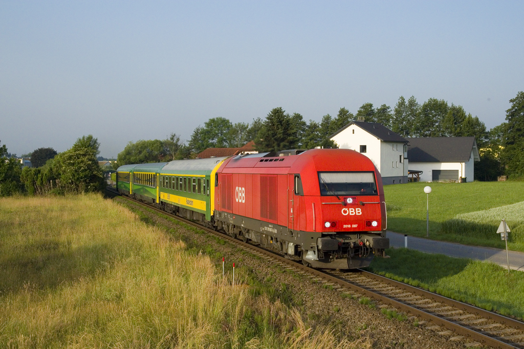 Am 13. Juni 2019 ist 2016 087 mit dem REX 317 (Graz Hauptbahnhof - Budapest Keleti pályaudvar) unterwegs, welchen sie bis zum Grenzbahnhof Szentgotthárd bespannen wird und hat soeben die Haltestelle Raaba verlassen. 