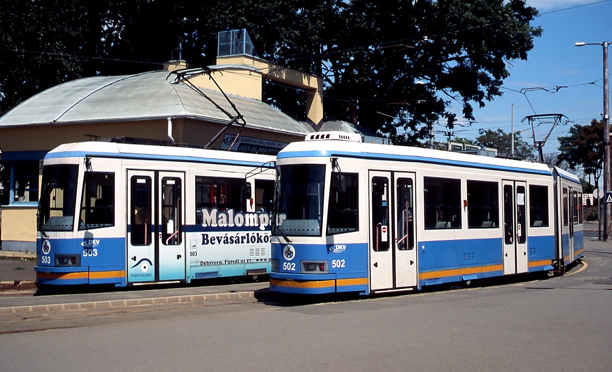Am 13.06.2011 stehen die Tw 502 und 503 in der Wendeschleife am Hauptbahnhof von Debrecen. Lediglich 11 Triebwagen vom Typ KCSV6 baute Ganz in Budapest zwischen 1993 und 1997 für die Straßenbahn in Debrecen, sie waren gleichzeitig die letzten in Ungarn entwickelten Straßenbahnfahrzeuge.