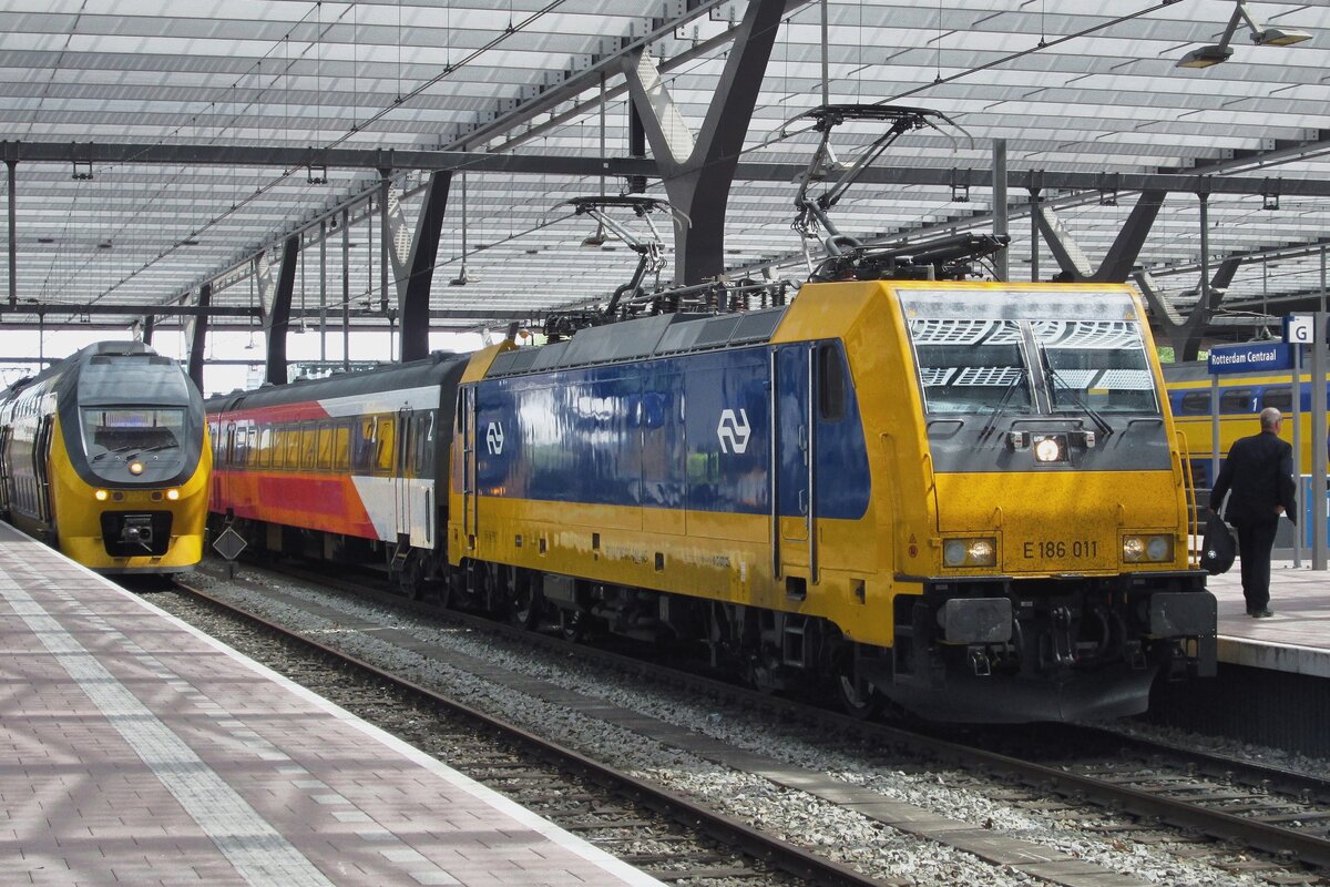 Am 14 Mai 2015 steht 186 011 in Rotterdam Centraal. Die Farben der IC-Wagen erinnern uns an der FYRA-Flopp, wobei 250 km/h Hochgeschwindigkeitszüge nicht schnell führten aber auf den Weg manchmal Unterteile verloren; Anlass für NMBS und NS die gesammte FYRA-Bestellung zu stornieren. Um das FYRA-Image noch ein kleines Bisschen aufrecht zu halten wurden Loks und Wagen in weiss-rosa-rot transformiert in 2013/14, aber in 2015 wurde alles auf blau-gelb zurückgesetzt um die Erinnerung an die grosste Flop immer der Niederlandische Staatseisenbahnen aus zu bannen. 