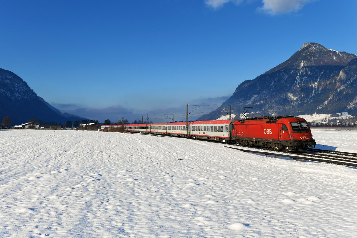 Am 15. Januar 2021 wollte ich am Nachmittag im Inntal Züge im Schnee aufnehmen. Aufgrund diverser Störungen kam allerdings kein einziger Güterzug durch. So wanderte allein ein Bild vom EC 89, geführt von 1216.024, auf die Speicherkarte. Entstanden ist es bei Niederaudorf, über der Lok thront das Kranzhorn.