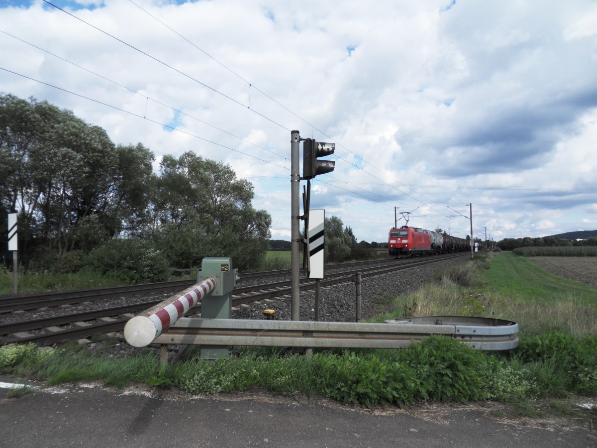 Am 16. August 2014 strebt eine 185 mit ihrem Kesselwagenzug am Bahnübergang bei Kilometer 26,0 in Richtung Ansbach.