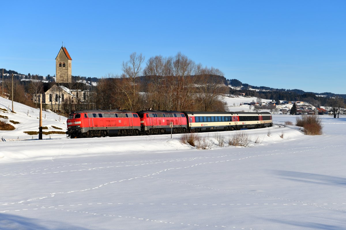 Am 17. Februar 2019 konnte ich bei Stein im Allgäu den EC 196 auf seiner Fahrt nach Zürich HB aufnehmen. Durch die noch winterliche Landschaft führten 218 497 und 498. Links im Bild sieht man die Pfarrkirche St. Mauritius, ein Bau aus der Zeit der Spätgotik. 