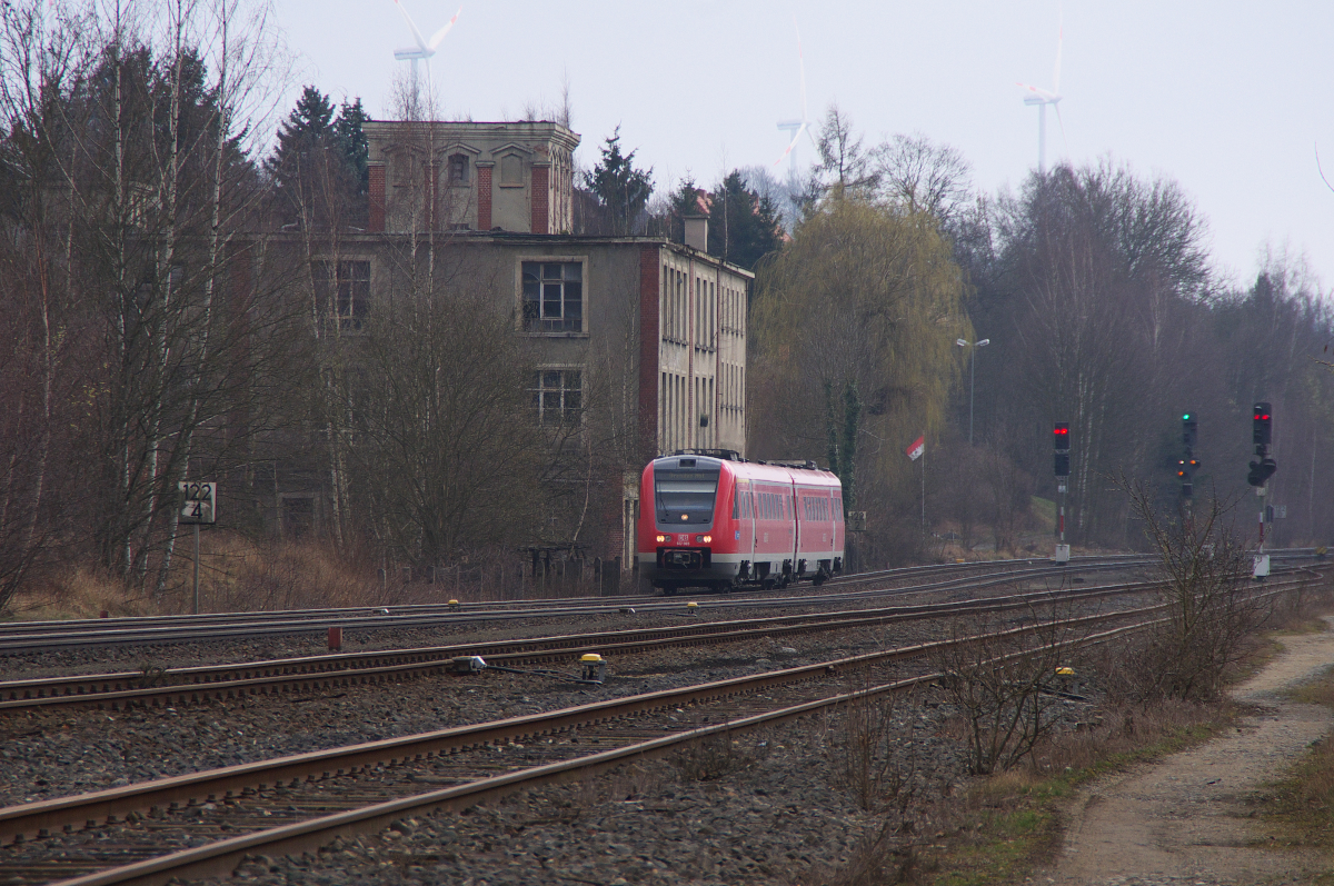 Am 17.03.2014 ist 612 065 auf der Relation Nürnberg - Dresden unterwegs.
Der RE hat gerade den Keilbahnhof und Bahnknoten Oberkotzau durchfahren und passiert gerade das Gebäude der ehemaligen Presshefe und Spiritusfabrik Scheibe und Scherdel Oberkotzau: In wenigen Minuten wird Hof Hbf. erreicht. Auch die Fabrik hatte früher einen Bahnanschluss. Die Güterwagen wurden im Anschluss per Seilzug befördert! Die Wagen wurden von der DB bereitgestellt und anschließend mit dem Seil in das Werksgelände gezogen. Die Wagen mussten in einer festgelegten Reihenfolge bereitgestellt werden! Die Produktion von Hefe und Schnaps in der Fabrik endete Mitte der 70er Jahre.