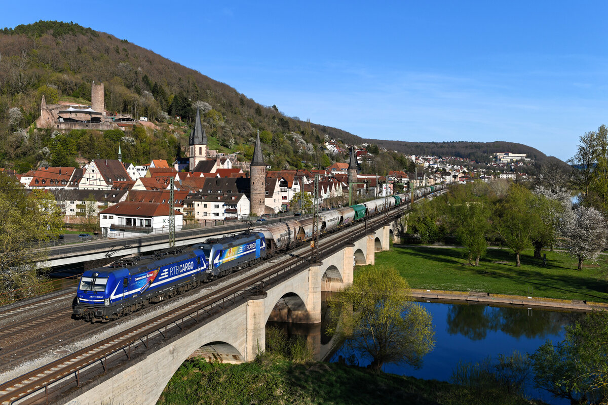 Am 18. April 2022 beförderten die für die Rurtalbahn Cargo fahrenden 193 791 und 824 einen aus Osteuropa kommenden Getreidezug westwärts. Bei Gemünden am Main konnte ich das attraktive Tandem mit seinem schweren Ganzzug vor der historischen Altstadt fotografieren. Zum Aufnahmezeitpunkt zeigte sich das Maintal bereits frühlingshaft.