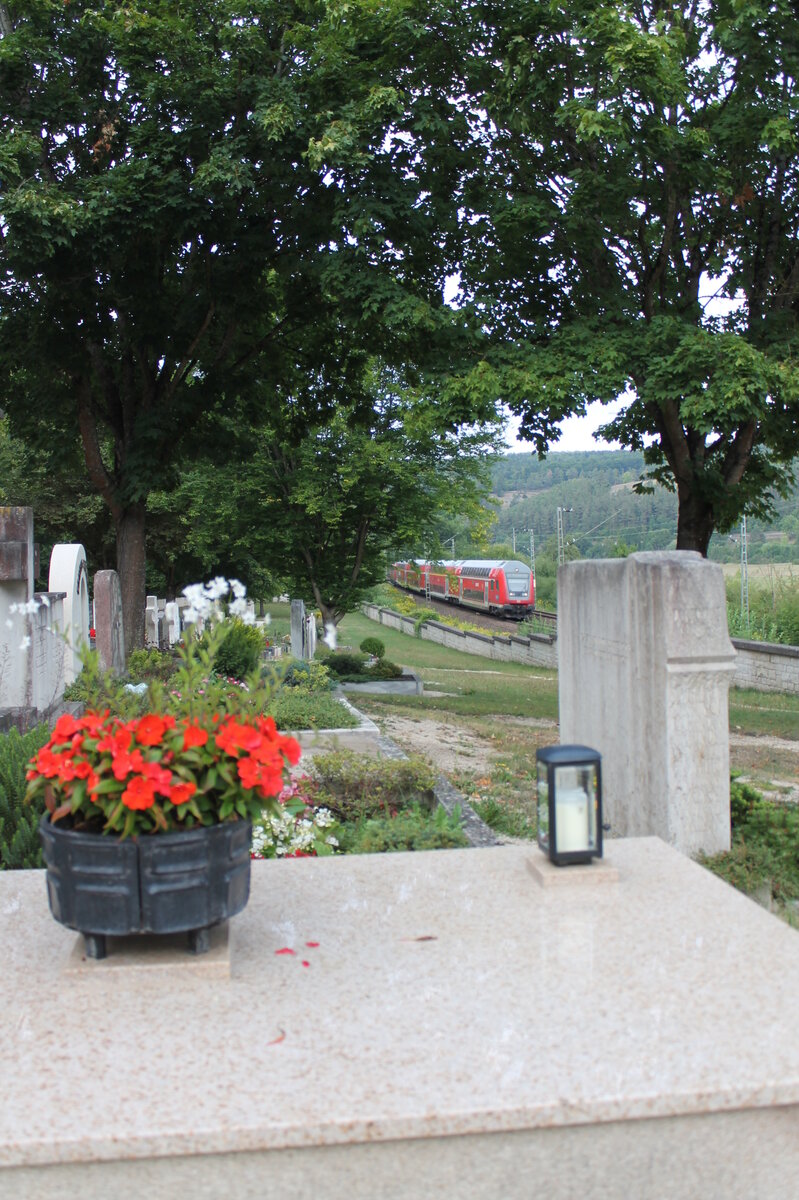 Am 18.08.2022 ist die Regionalbahn von Treuchtlingen nach München unterwegs. Hier fährt sie am Friedhof in Solnhofen vorbei.