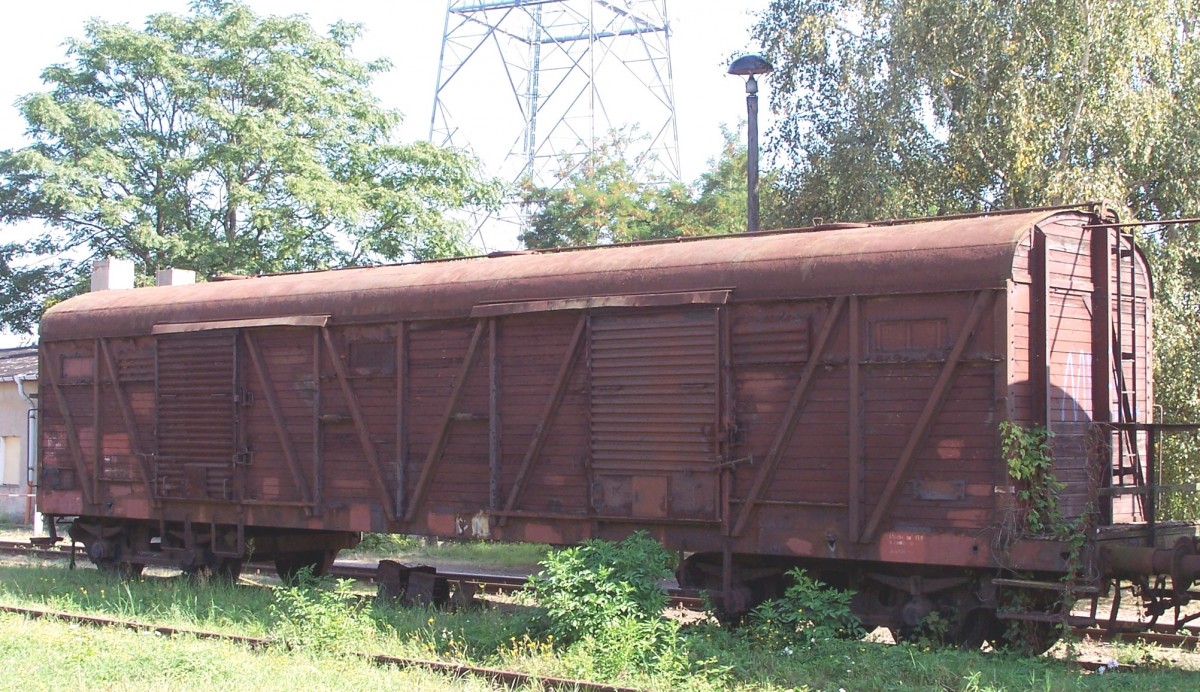 Am 19.9.2009 aufgenommen von der Straße im Magdeburger Binnenhafen:
Ein gedeckter 4-Achser der DR, Gagms-v, GSN 197. Erste Baujahr 1954. Diese Wagen waren recht langlebig, die letzten stellte die DR erst beim großen Aufräumen Anfang der 90-Jahre ab. Auch wenn das eine Nachkriegsbauart ist- man erkennt doch deutlich die  Verwandtschaft   zur Kriegsbauart  Bromberg . Der Wagen war wohl Arbeitsvorrat für die dortigen Museumseisenbahner.