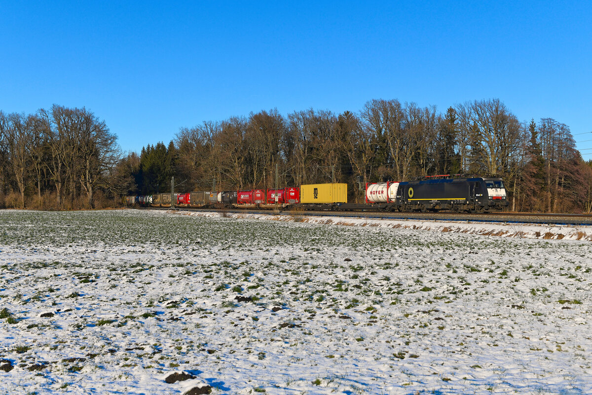 Am 20. Januar 2024 verkehrte der KLV-Zug DGS 44891 aus Waalhaven Zuid nach Norditalien. Bespannt wurde dieser von der bei Beacon Rail angemieteten 189 990. Eigentlich wollte man bei TXLogistik ja keine Lok der Baureihe ES 64 F4 mehr einsetzen, nun scheint man aber aufgrund Lokmangels eine Ausnahme zu machen. Die 189 990 war einige Zeit mit einer attraktiven Folierung für SBB Cargo in Einsatz und bespannte häufig den Stahlzug aus Göttingen. Über der Frontscheibe erkennt man noch ein Stück der ehemaligen Gestaltung im Grundton grau. Die Aufnahme entstand bei Brannenburg im Inntal.