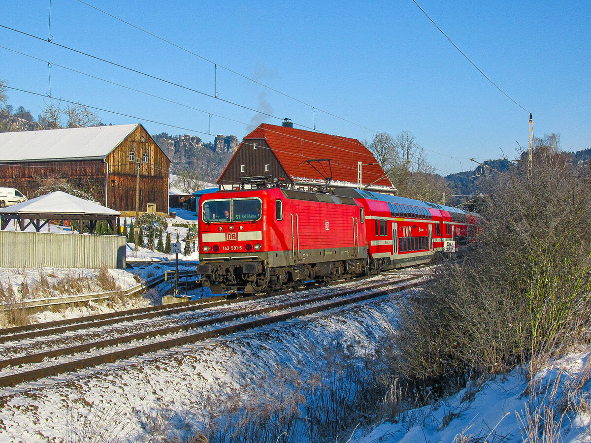 Am 20.01.2024 zog die Dresdner Lady 143 591-6 (Nvr: 91 80 6143 591-6) mit der S1 nach Bad Schandau. Hier bei der Vorbeifahrt am bekannter Fachwerkhaus in Kurort Rathen um 10:45 Uhr.