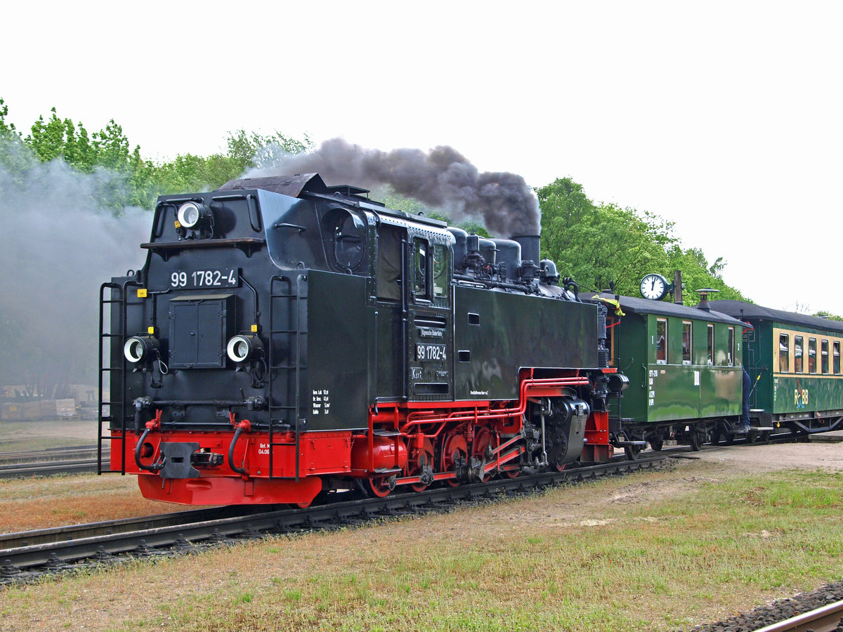 Am 20.05.2017 wartet 99 1782-4 in Putbus (Rügen) auf die Abfahrt nach Göhren. 
Soeben wurde der kleine Zweiachser KAB 971-210 zwischen Lok und Regelzug gekuppelt. Er wurde für diese Fahrt von einer Privatgruppe angemietet. Der schöne Wagen wirkt hinter der doch recht großen 750mm-Schmalspurlok sehr klein.
