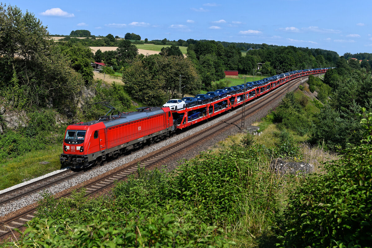 Am 21. Juli 2021 beförderte die 187 184 von DB Cargo den Autotransportzug GA 60016 von Dingolfing nach Maschen Rbf. Geladen hatte dieser BMW Neuwagen der 4er, 5er und 6er Reihe. Interessant ist die Tatsache, dass sich der Automobilproduzent für den Neuwagentransport auf mehrere EVUs stützt. Neben DB Cargo sind auch TXLogistik und Rurtalbahn Cargo im Geschäft. Entstanden ist die Aufnahme des Zuges mit seiner mehrere Millionen Euro an Wert darstellenden Fracht bei Laaber in der Oberpfalz. 