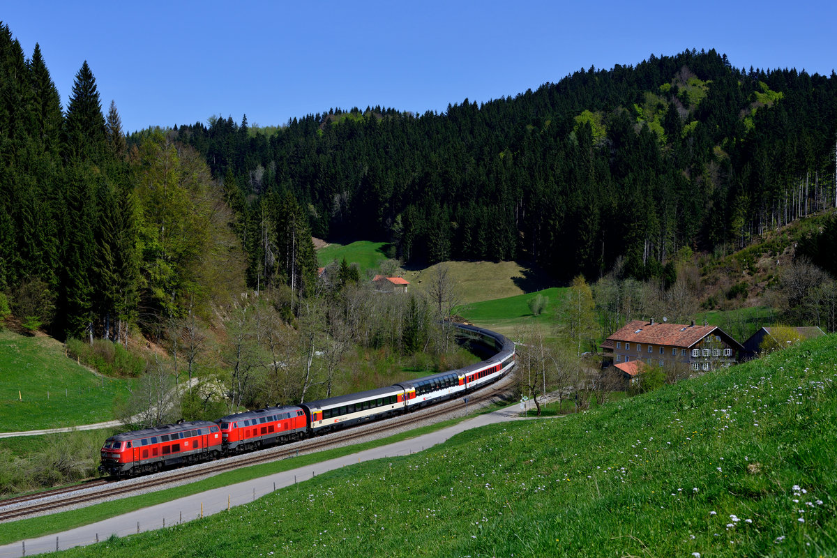 Am 22. April 2018 brachten die Ulmer 218 436 und die Mühldorferin 218 403 den EC 193 von Lindau nach München HBF. Baustellenbedingt verlief die Fahrt über Kempten, was den Reisenden - insbesondere im Panoramawagen - reizvolle Landschafts-Eindrücke bescherte. Bei Mutten passierte der Zug ein für diese Gegend typisches Gehöft. Einen Baukran im Hintergrund habe ich digital wieder abgebaut.