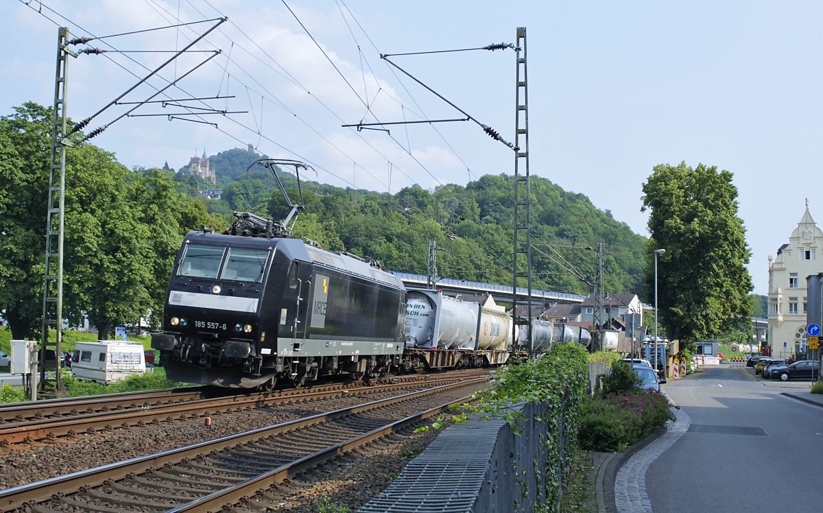 Am 22.07.2021 durchfährt die MRCE-185 557-6 Königswinter in Richtung Norden, im Hintergrund Drachenburg und Drachenfels