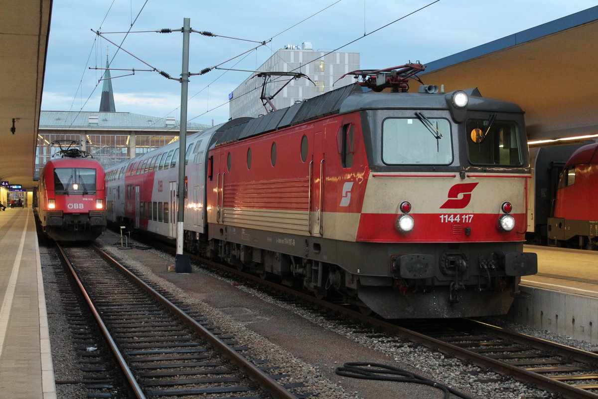 Am 22.9.2014 steht die 1144 117  Schachbrett  mit einem REX in Wien West und wartet neben der 1016 032 mit einem REX200 auf die Abfahrt.