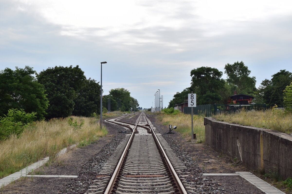 Am 23.7.20 stand die Bahnstrecke Biederitz - Altengrabow auf dem Programm. Besonders auffällig an der Strecke ist das alle Haltepunkte und Bahnhöfe bis Loburg Barrierefrei mit 55cm Bahnsteigen ausgebaut und modernisiert sind was für eine Strecke ohne Personenverkehr ziemlich unüblich ist. 2003 wurde die Strecke samt Bahnsteige bis Loburg modernisiert. 2011 wurde der Personenverkehr wegen Oberbaumängeln und der daraus resultierenden bedeutend längeren Fahrzeit auf einen dauerhaften Busnotverkehr umgestellt. Seit 2015 betreibt die RegioInfra die Strecke welche noch gelegentlich für Bundeswehr Transporte genutzt wird. Hier sieht man vom Bahnübergang aus den Bahnhof Büden. Dieser verfügt über Trapeztafeln als Einfahrsignale. Die Weichen sind mit gekuppelten Riegelhandschlössern gesichert. Ebenso verfügte Büden einst über eine Verladerampe welche rechts im Bild zu sehen ist.

Büden 23.07.2020