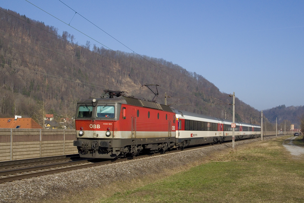 Am 25. März 2021 eilt 1144 103 mit dem D 619 (Schwarzach-St. Veit - Graz Hauptbahnhof) bei Graz - Raach in Richtung Zugendbahnhof, den der Zug in wenigen Minuten erreichen wird. 