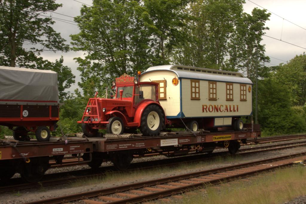 Am 2.5.2015 kam Zirkus Roncalli nach Bielefeld. Im Bahnhof Bielefeld Ost konnte ich auch einige Wagen des ersten Zugteils ablichten. Darunter war als Schlußwagen auch diese Zirkus Garnitur mit einem Roncalli Hanomag Schlepper, die auf einem Transwaggon transportiert wurde.