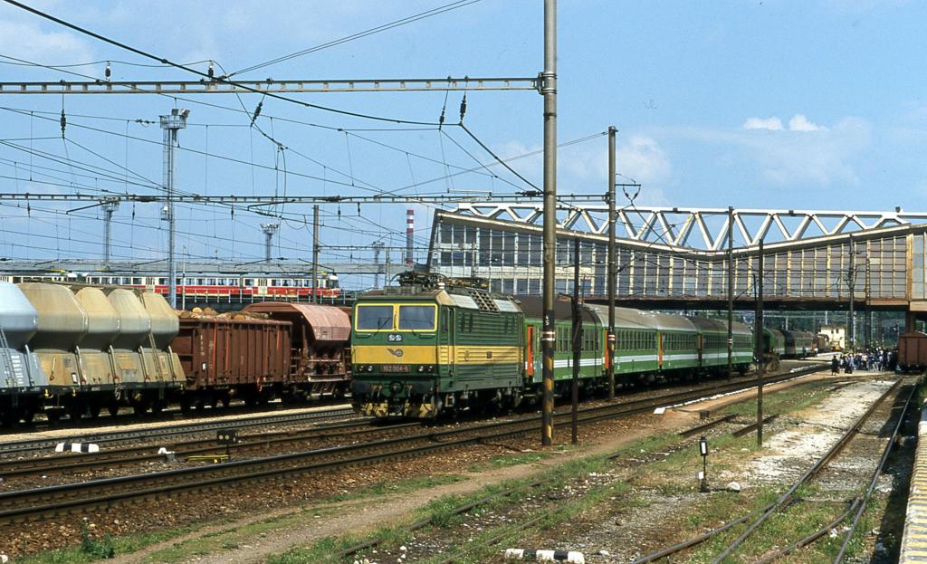 Am 26.06.2001 steht eine komplette OS Garnitur mit Lok 182004 auf dem
Abstellgleis im Bahnhof Poprad Tatry. Das Foto zeigt deutlich den oberen
quer zu den Gleisen des Fernbahnhof verlaufenden Schmalspurbahnhof. Nach links
weg fahren dort die Zge in Richtung Hohe Tatra.