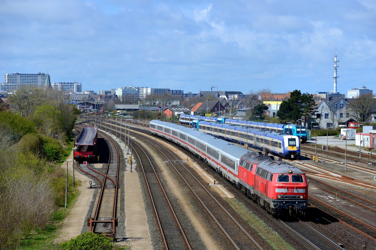 Am 28. April 2016 konnte ich bei Tinnum 218 307 und 344 mit ihrem IC 2315 nach Frankfurt am Main HBF ablichten. Die Maschinen beschleunigen den Zug gerade aus dem Bahnhof Westerland heraus. Bei dem Blick auf das Dach von 218 307 fällt die Voith-Kühlanlage auf. Diese wurde selten verwendet, die Lamellen öffnen längs zum Lokkasten. Diese Kühlanlage ist die markanteste unter den in der Baureihe 218 verbauten: Unter voller Belastung arbeitet sie heulend und hochfrequent. Die 'Dachjalousien' werden durch den von den Lüfterrädern erzeugten Luftdruck geöffnet. Kommt die Lok zum Stillstand, schliessen die Lamellen mit lautem Klappern. 218 307 dürfte einer der letzten existierenden Exemplare der Baureihe sein, die über die Voith-Kühlanlage verfügt.