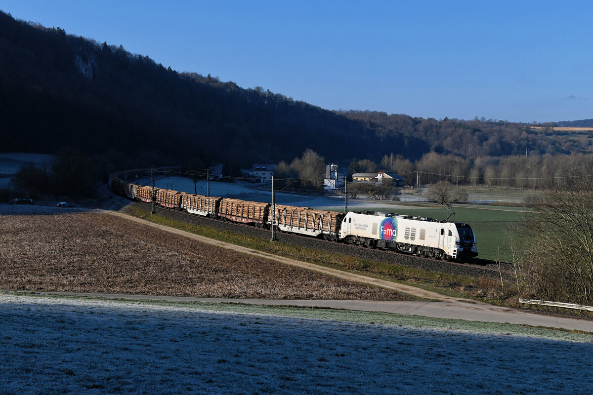Am 28. Februar 2021 war die Strecke zwischen Nürnberg und Regensburg baustellenbedingt gesperrt. Daher war im landschaftlich reizvollen Altmühltal einiges an umgeleiteten Güterzügen zu erwarten. Der Tag begann gleich vielversprechend. Noch im Auto nach der passenden Fotostelle für die morgendlichen Leistungen suchend, erblickte ich den sich nähernden Holzzug DGS 69146 von Brügge (Westf.) nach Hengersberg bei Breitenfurt. Schnell herausgesprungen, die Kamera gepackt und in die mit Rauhreif überzogene Wiese gelaufen ging sich noch dieser Notschuss auf die Euro Dual 159 201 von HHPI mit ihrem mit Stammholz beladenen Umleiterzug aus. 