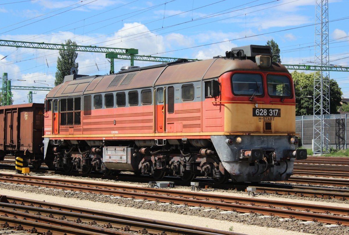 Am 28.07.17 fährt 628 317 mit einem offenen Güterzug in Székesfehérvár Richtung Osten aus.