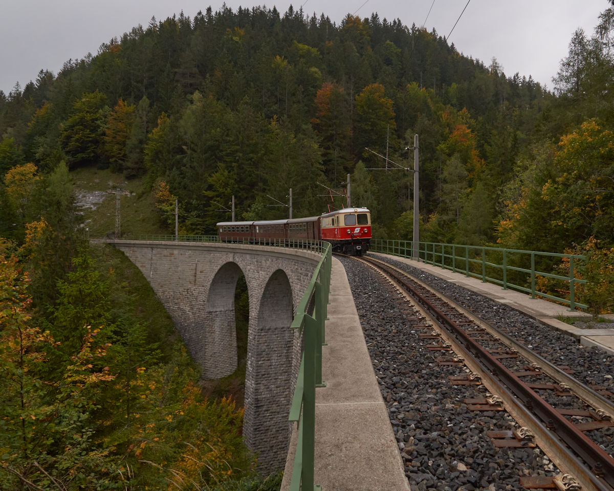 Am 29.09.2021 war NVOG E14 (als 1099.014 der BB) mit einem Personenzug auf dem Weg in Richtung Mariazell. Gerade wird der Saugrabenviadukt berquert (Fotohalt).