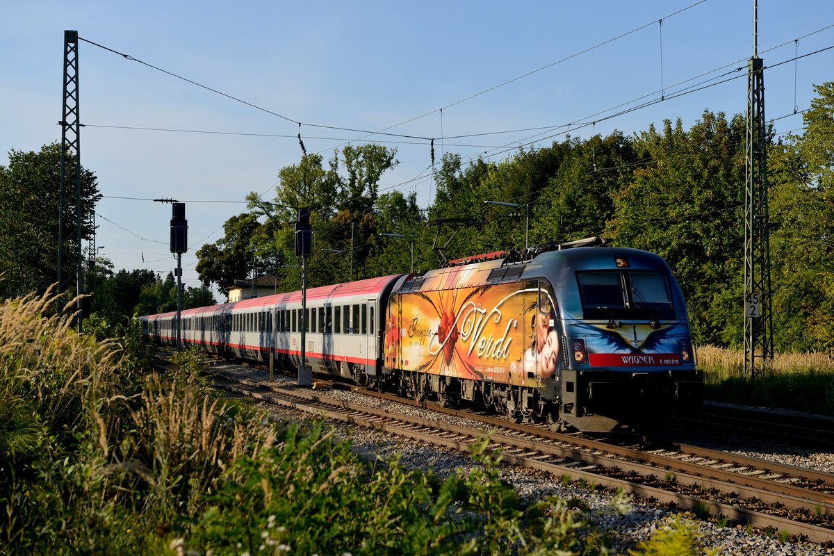 Am 30. August 2013 war EC 189 von München nach Innsbruck mit der Wagner/Verdi-Lok 1216 019 bespannt. Im schönen spätsommerlichen Abendlicht gelang diese Aufnahme bei der Durchfahrt durch den Bahnhof Assling.