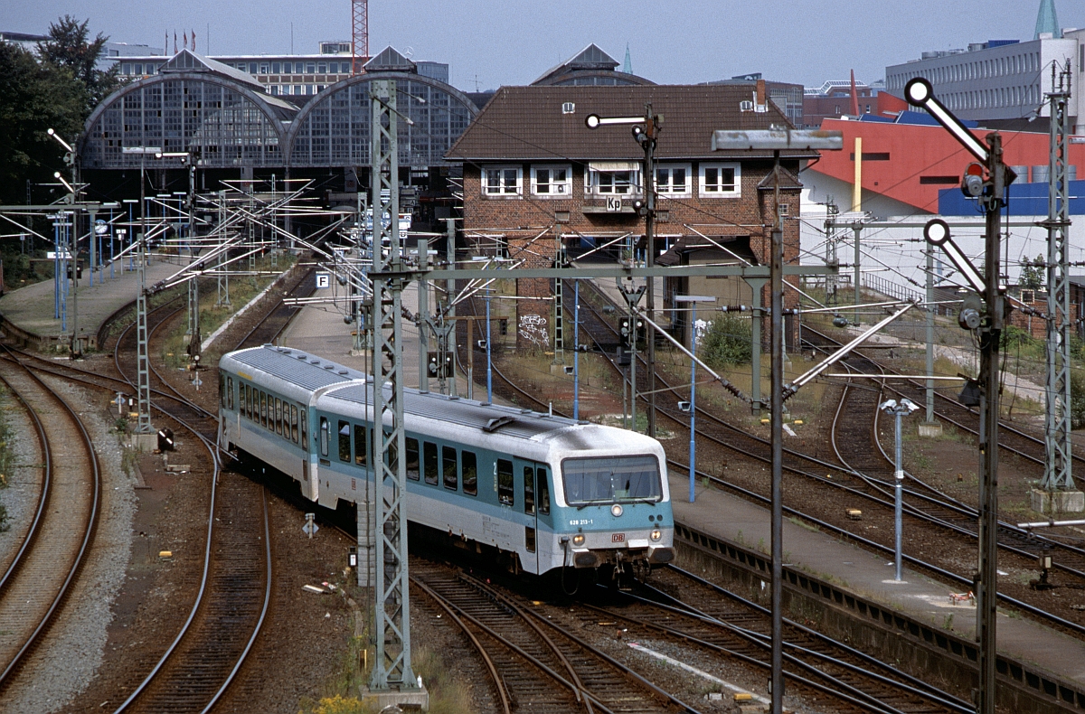 Am 30.8.1999 dominiert in Kiel Hbf optisch bereits der Drahtverhau, Reiterstellwerk, Formsignale und die alten Bahnhofshallen gibt es aber noch. Ausfahrend 628 213.