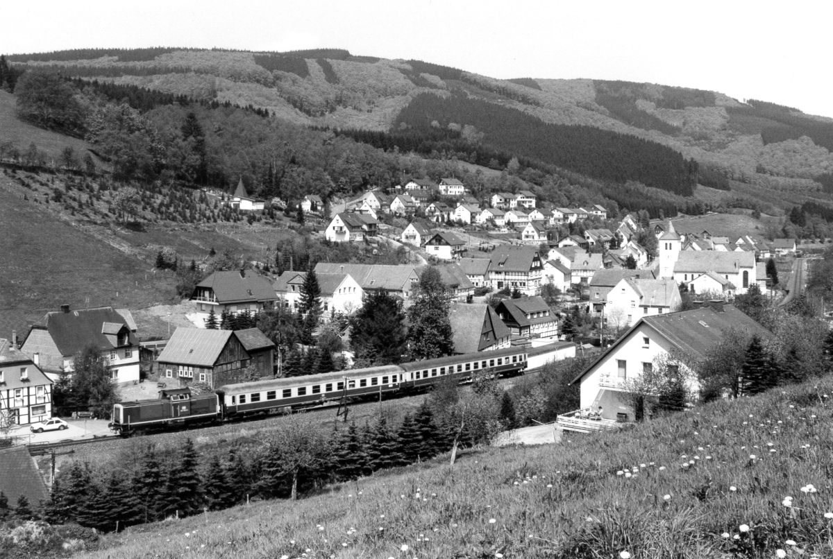 Am 4.8.1990 ist die Hagener 212 307 mit ihrem kurzen Eilzug bei Wulmeringhausen nach Winterberg unterwegs.