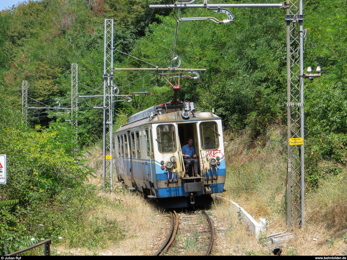 Am 5. August 2013 erreicht ein Triebwagen der Ferrovia Genova-Casella die Station Pino. An diesem warmen Sommertag bleibt die Führerstandstüre des Triebwagens offen, damit der Zugbegleiter den Fahrtwind geniessen kann. Die Züge der FGC verkehren alle begleitet. 
