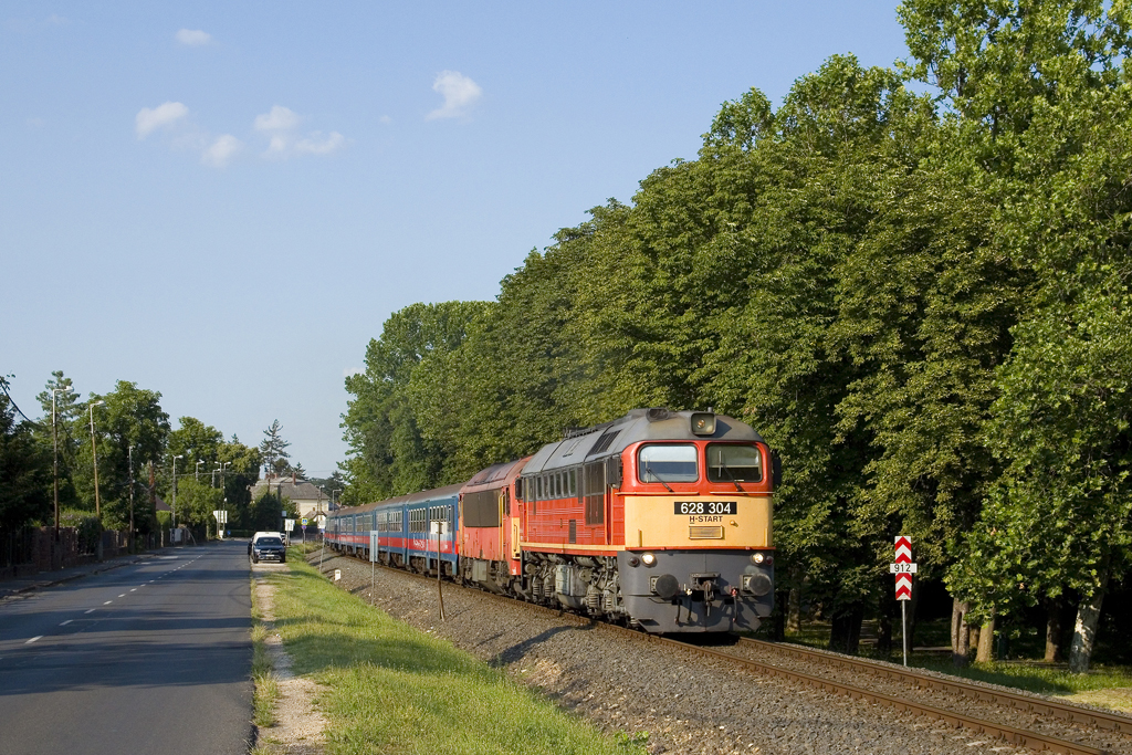Am 9. Juli 2023 wurde im Bahnhof Révfülöp ein Tehervonat angekündigt. Selbiger entpuppte sich als Leerpersonenzug mit den Loks 628 304 und 418 304. Nach einem Kreuzungsaufenthalt konnte der Zug kurz nach der Ausfahrt aus dem Bahnhof fotografiert werden. 