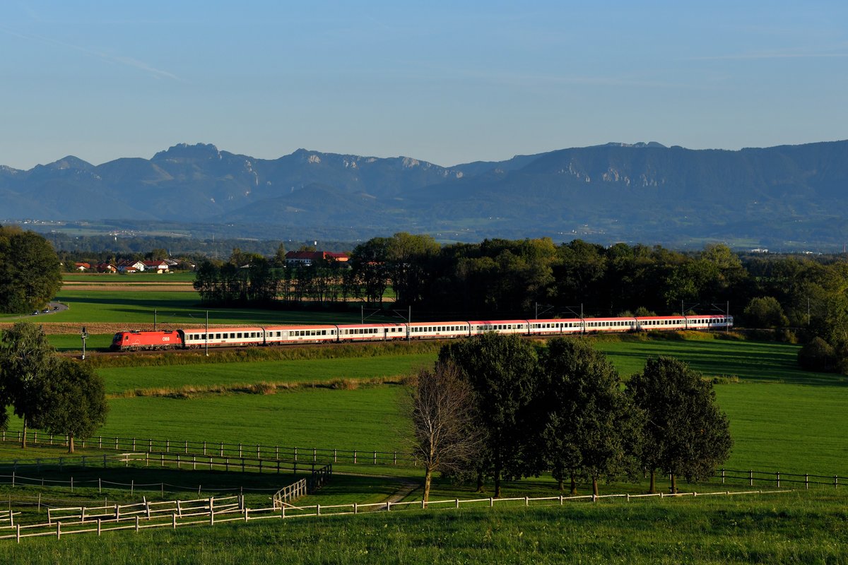 Am Abend des 01. Oktober 2019 eilte 1216.021 mit ihrem EC 84 von Bologna Centrale durch das bayerische Voralpenland bei Aubenhausen ihrem Endpunkt München HBF entgegen. Der klare Herbsttag sorgte für gute Fernsicht auf die Chiemgauer Alpen samt Kapenwand. 
