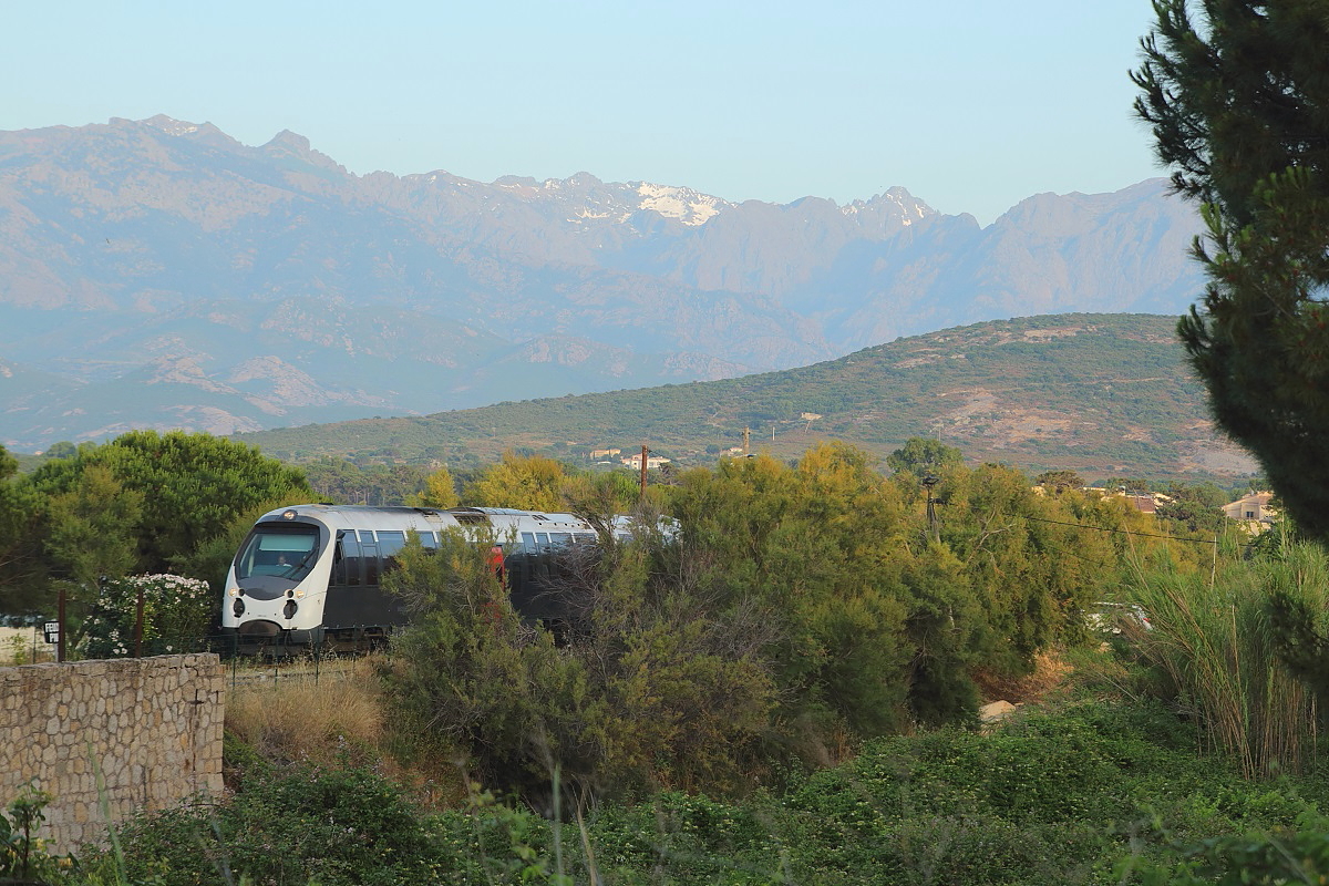 Am Abend des 08.06.2014 erreicht eine AMG 800-Garnitur den Bahnhof Calvi. An den Nordflanken der bis 2.700 m hohen korsischen Berge liegen trotz der sommerlichen Temperaturen an der Küste noch Schneereste.